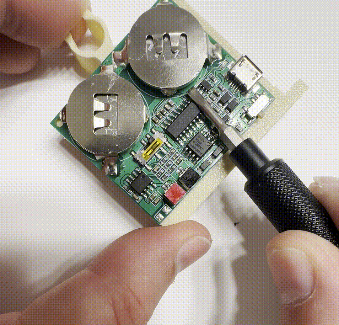 A screwdriver pushing a CR2032 battery out of its holder